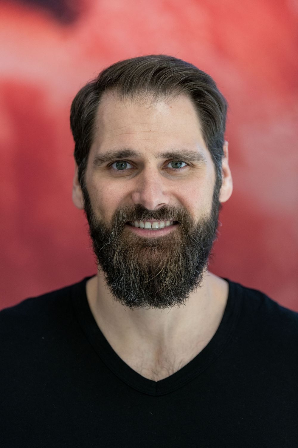 a bearded man looks at the camera while having his picture taken at an event by a professional photographer
