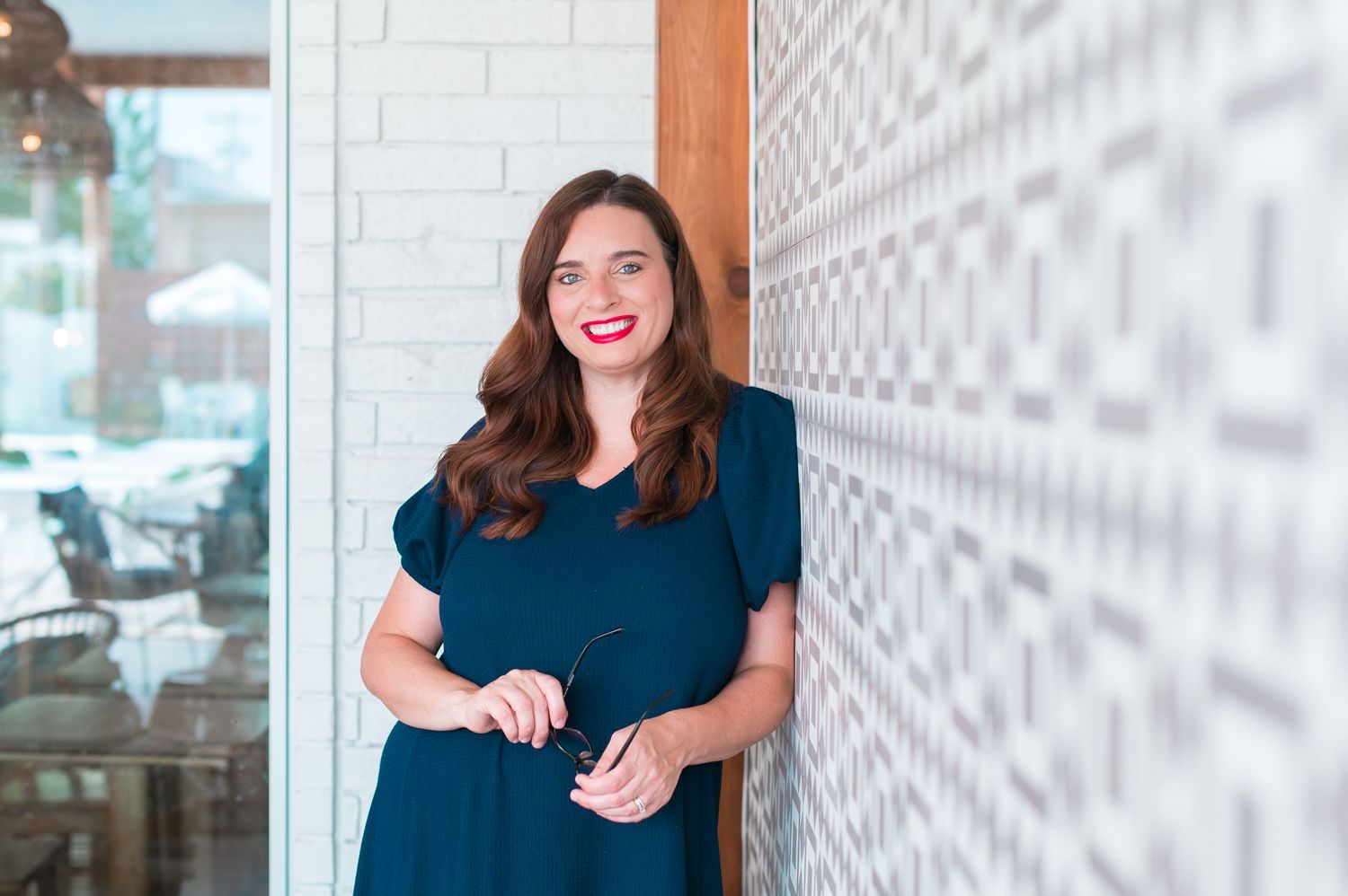 Approachable businesswoman with glasses and design wall in tulsa oklahoma