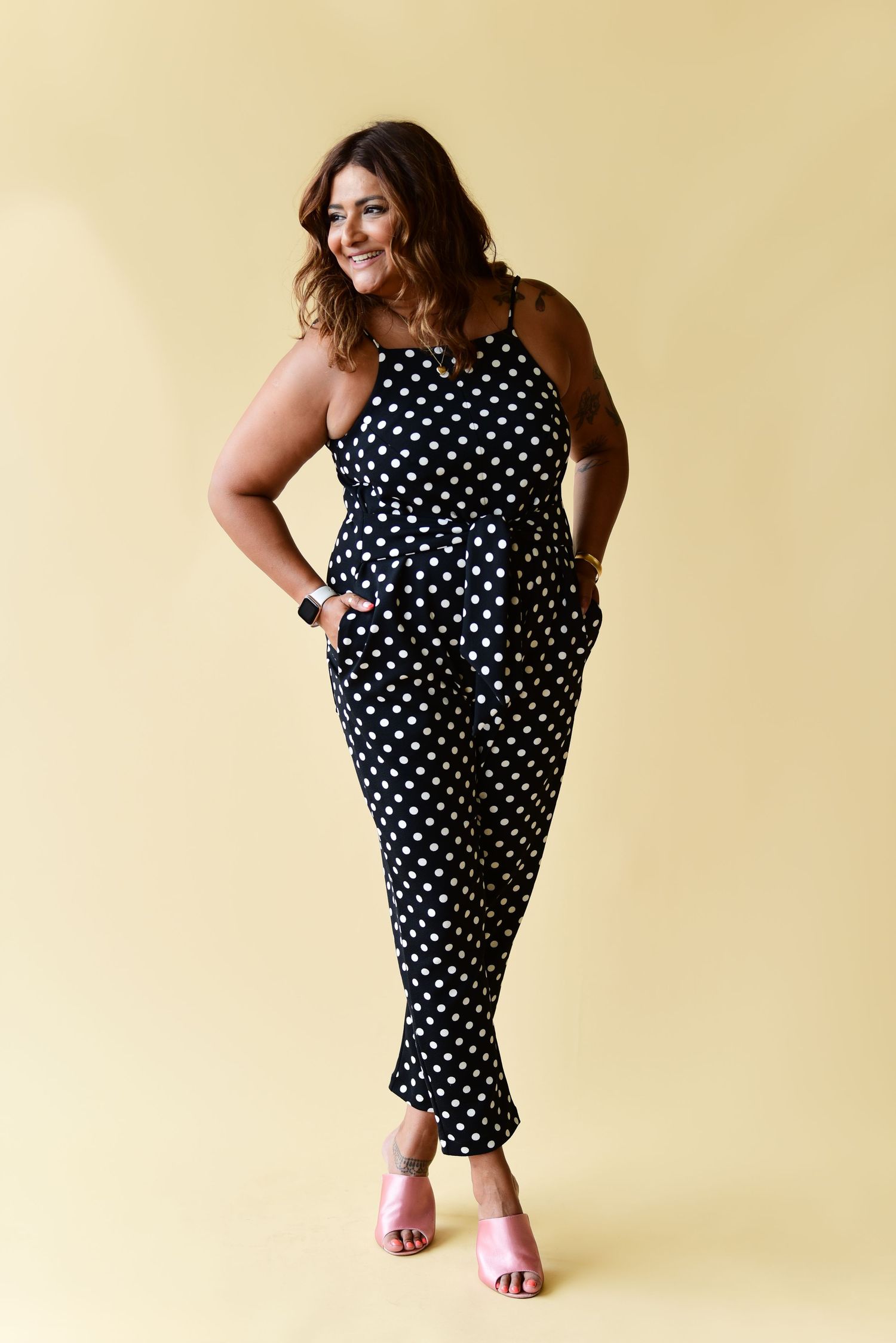 A polka dot jumpsuit with fitted silhouette and tapered legs styled against a neutral backdrop.