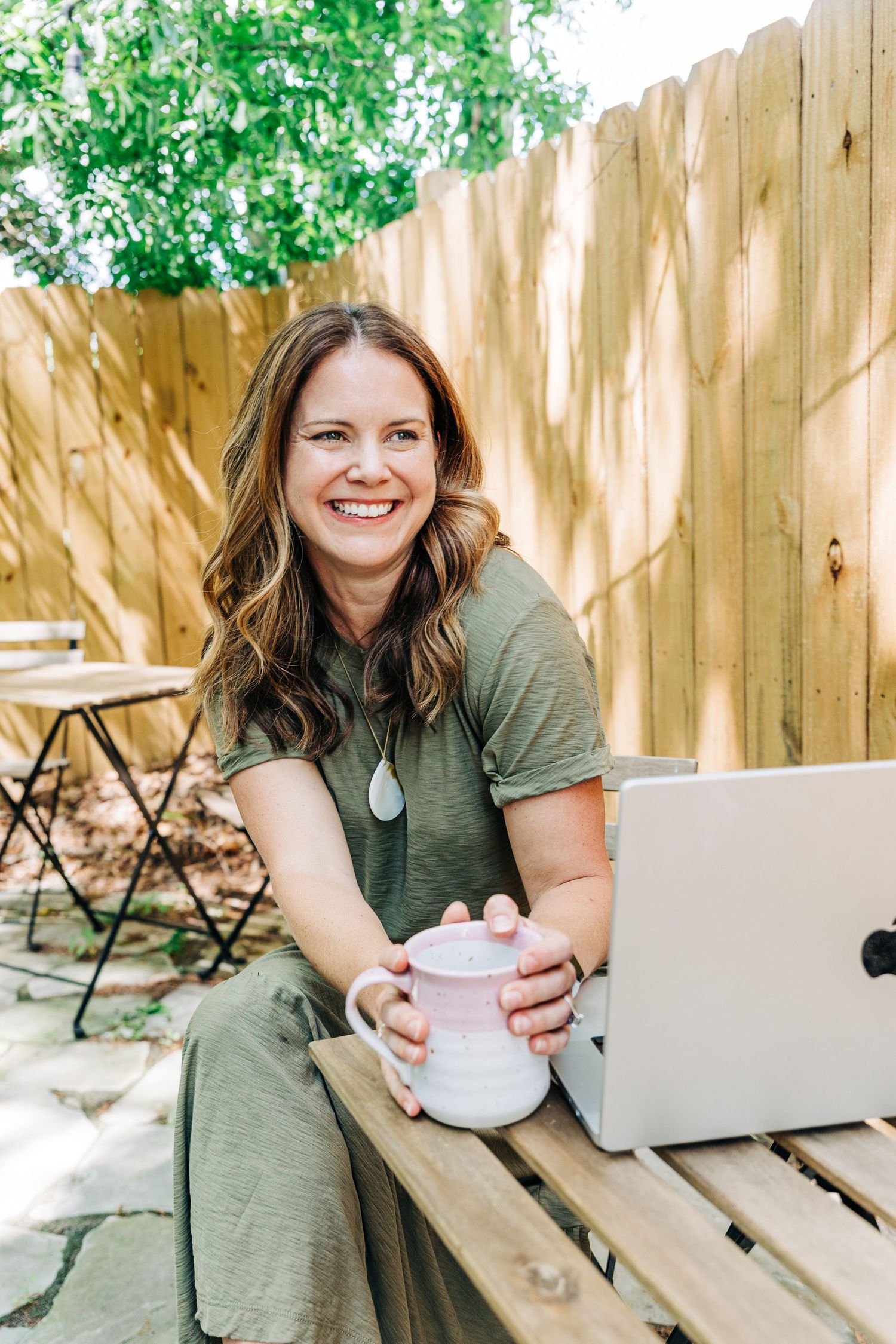 brand photographer sitting outside for her own branding photos with her laptop and coffee at Little Villa Charlotte