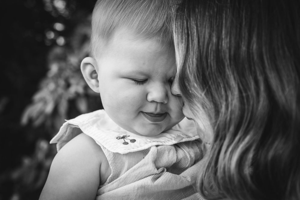 A black and white intimate portrait of a baby and parent sharing a joyful moment.