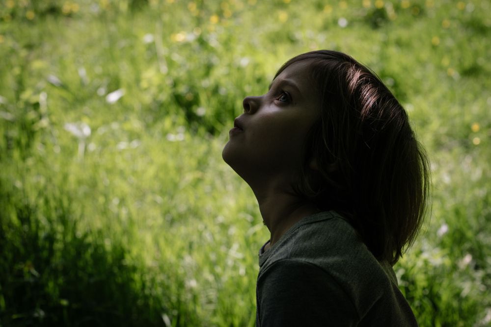 Profile silhouette against green nature background with upward gaze.