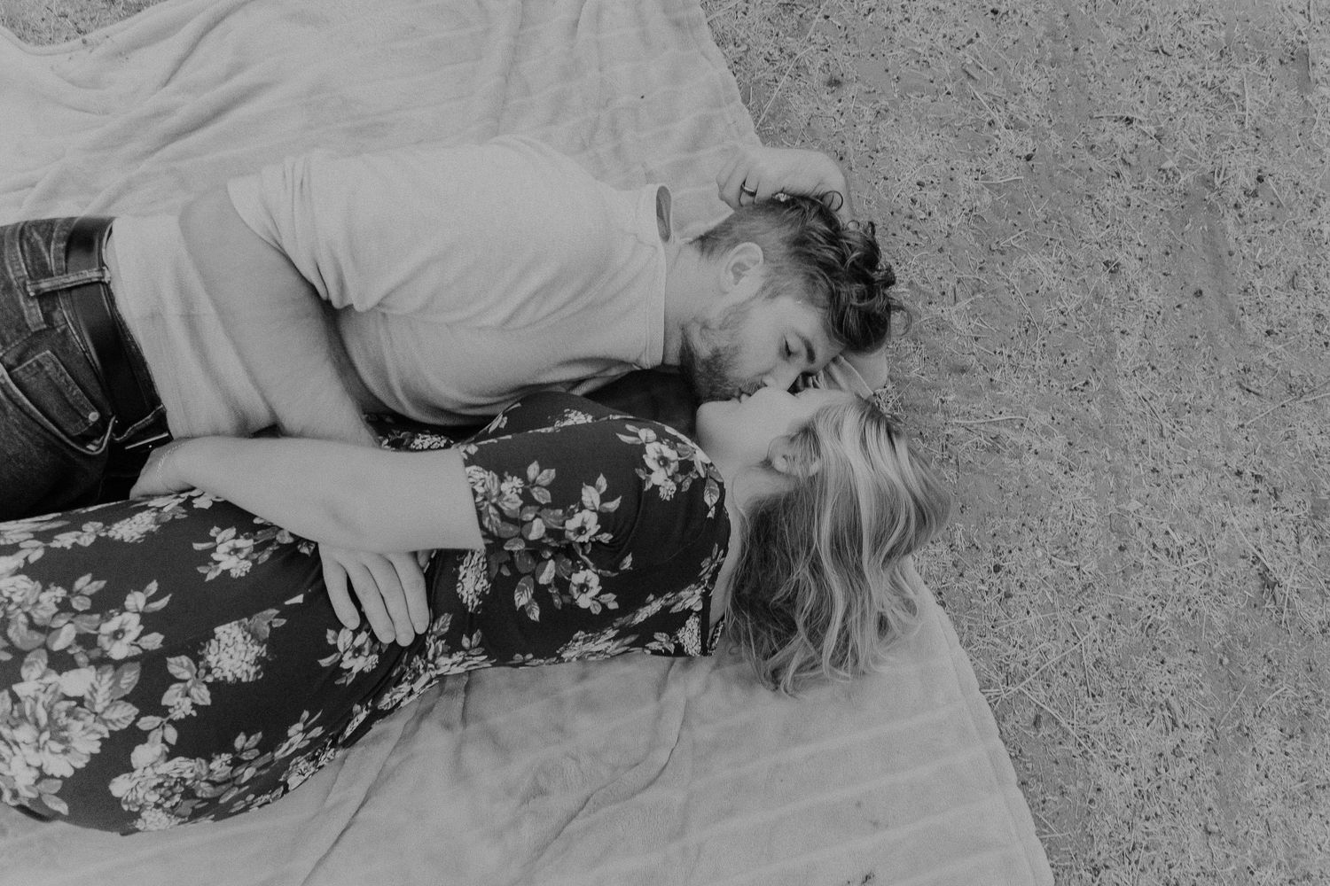 A black and white portrait of a couple sharing a tender moment outdoors.