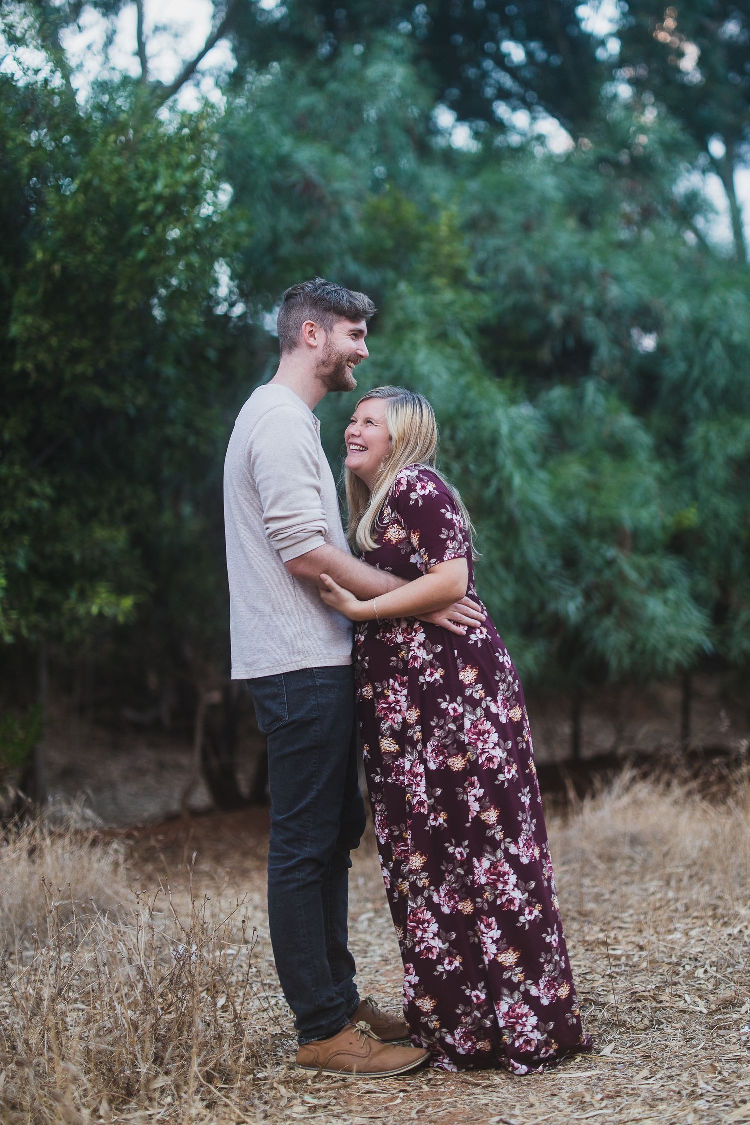 Two people embracing and laughing together in a natural outdoor setting.