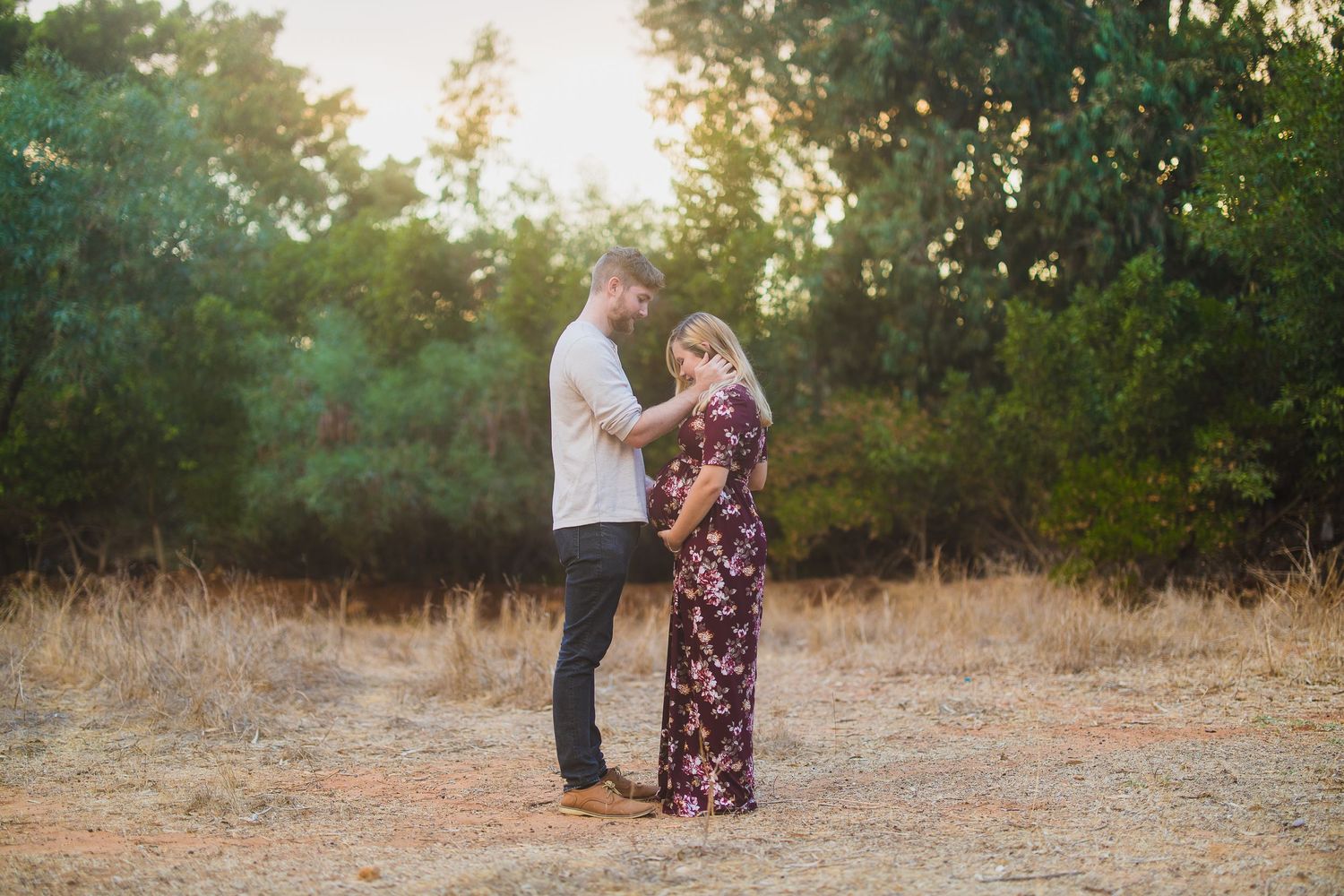 Couple standing close together in a rustic outdoor setting at golden hour.