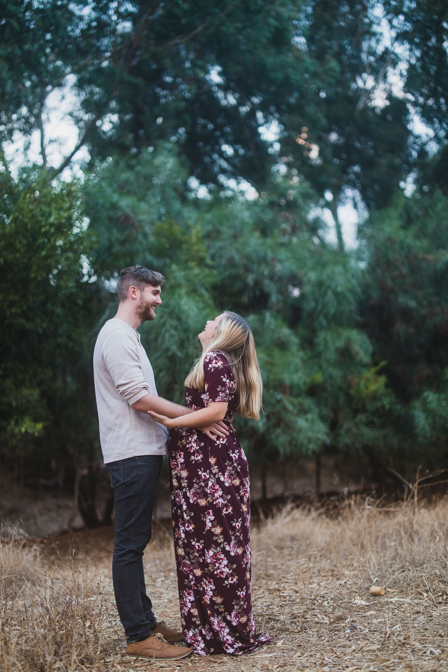 A couple sharing a tender moment while standing in a wooded area.