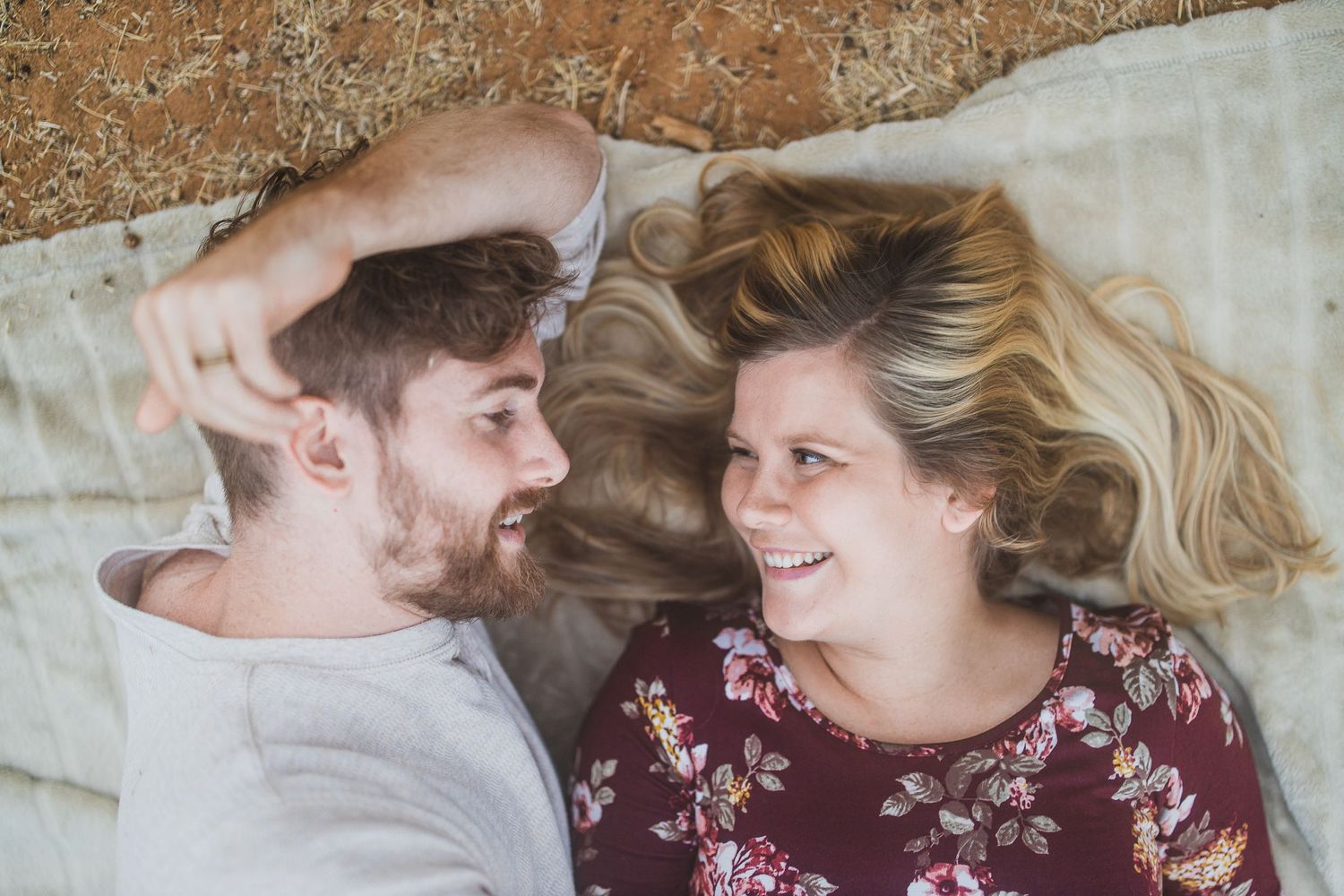 A couple lying on a blanket outdoors sharing laughter and joy together.