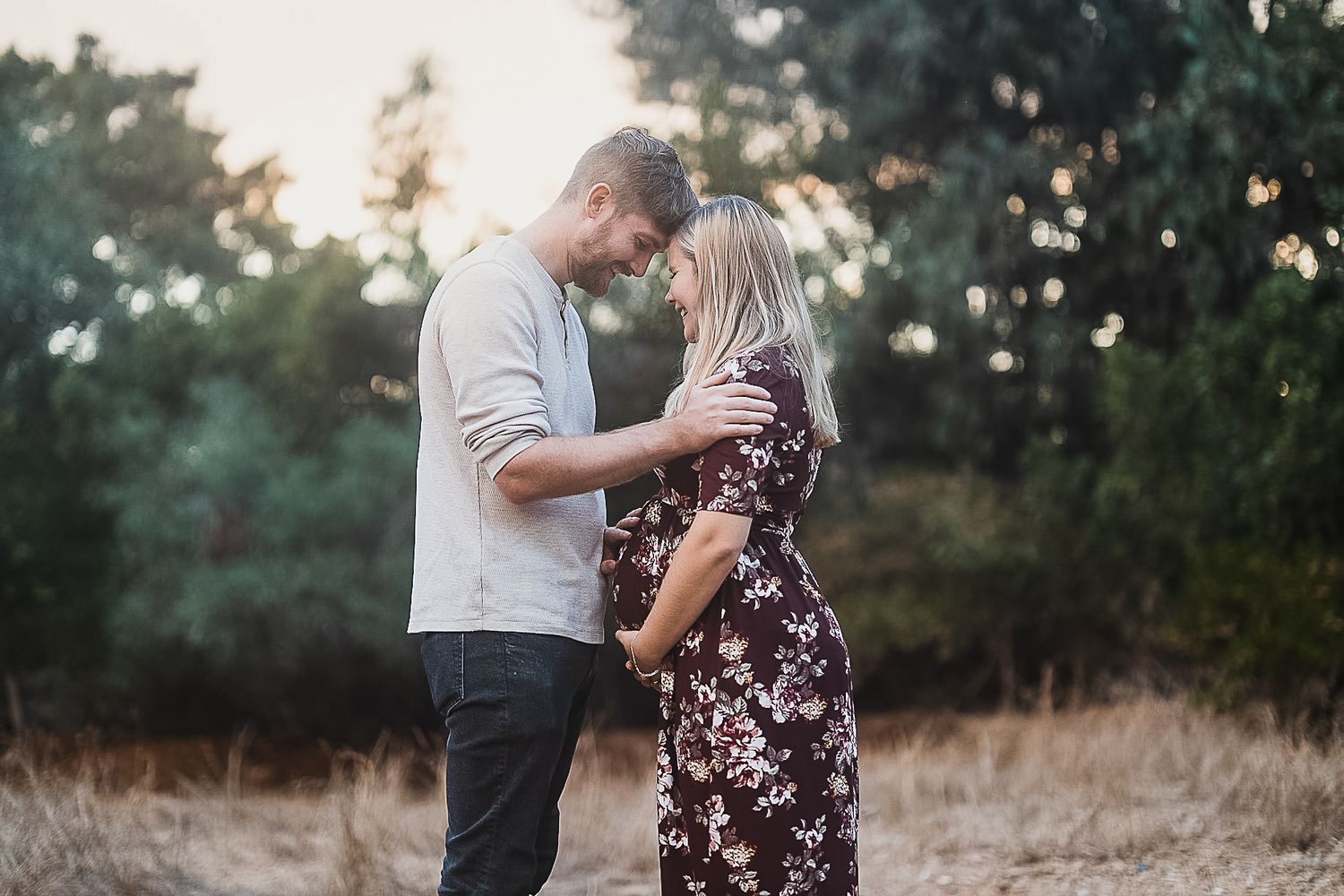 Intimate moment between couple during outdoor maternity photoshoot.