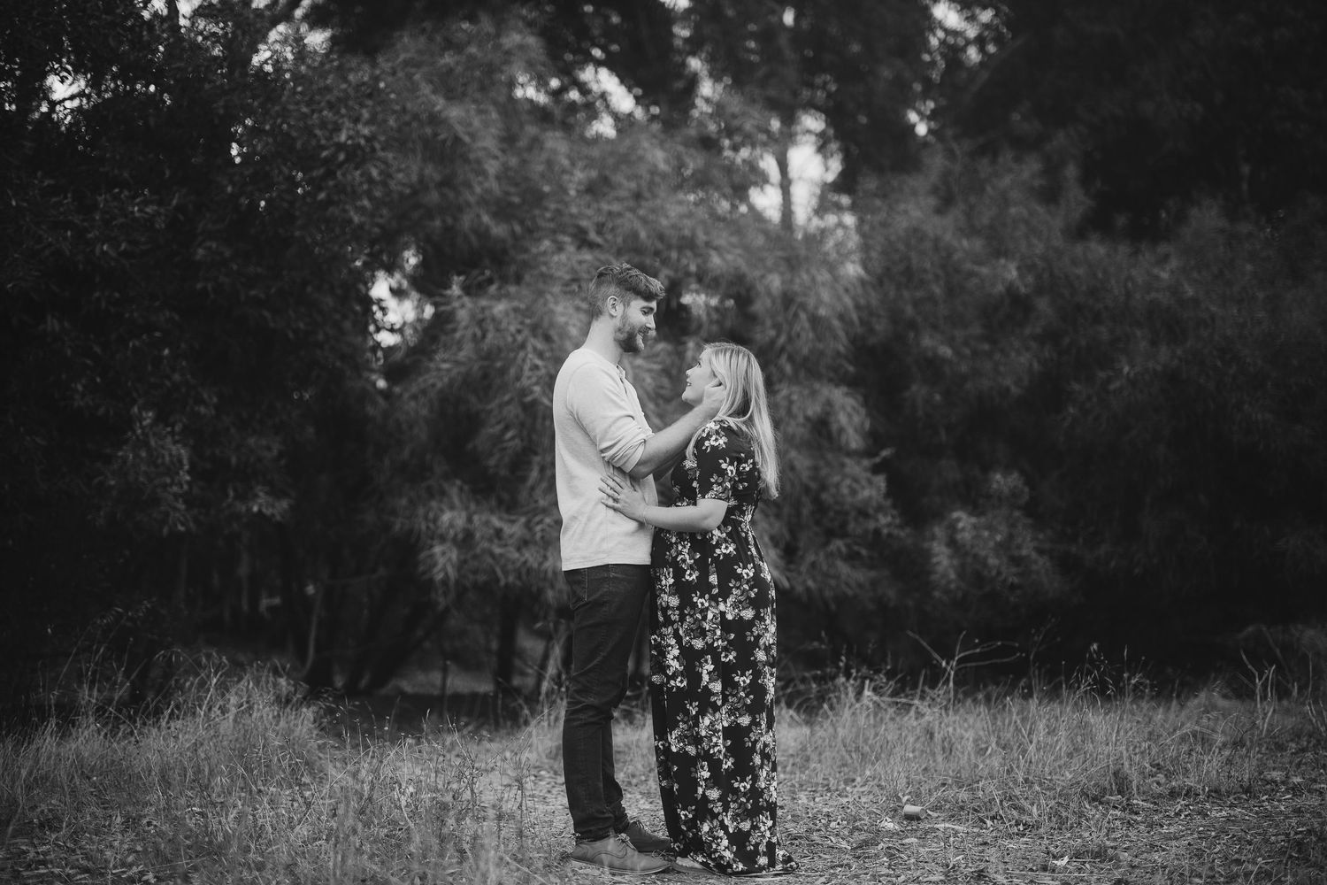 Black and white capture of a couple's tender moment in a natural outdoor setting.