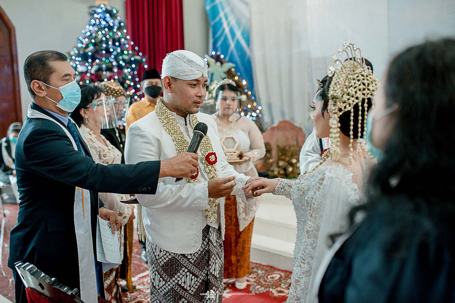Wedding ceremony taking place in a church with Christmas decorations and traditional attire.