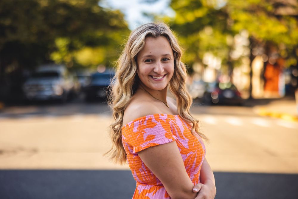 Orange floral off-shoulder dress worn in outdoor summer setting with natural lighting.