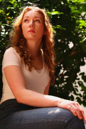 Portrait in natural lighting with sunlit foliage background showing contemplative expression.