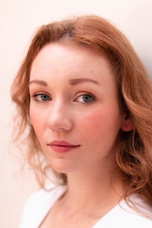 Gentle closeup portrait with soft lighting and natural makeup against white background.