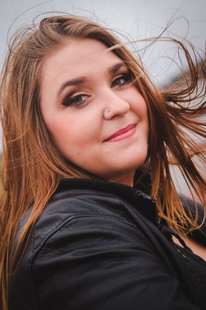 Candid closeup with windswept hair and natural smile against blurred background.