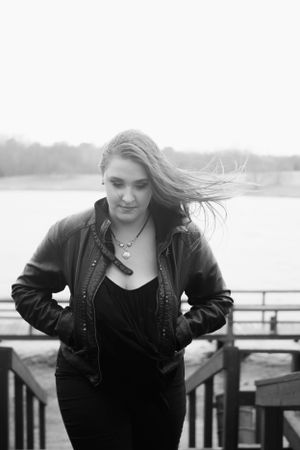 Wind-swept portrait on a waterfront deck in black and white.