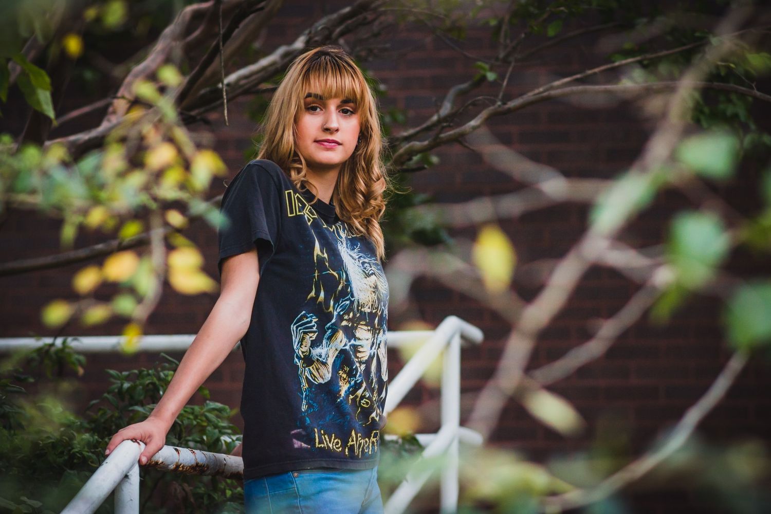 Artistic outdoor portrait with natural lighting and casual band t-shirt style.
