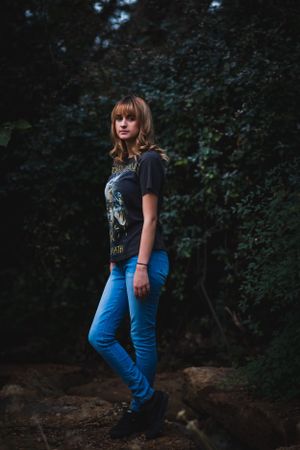 Moody forest portrait of someone in a band t-shirt and blue jeans.