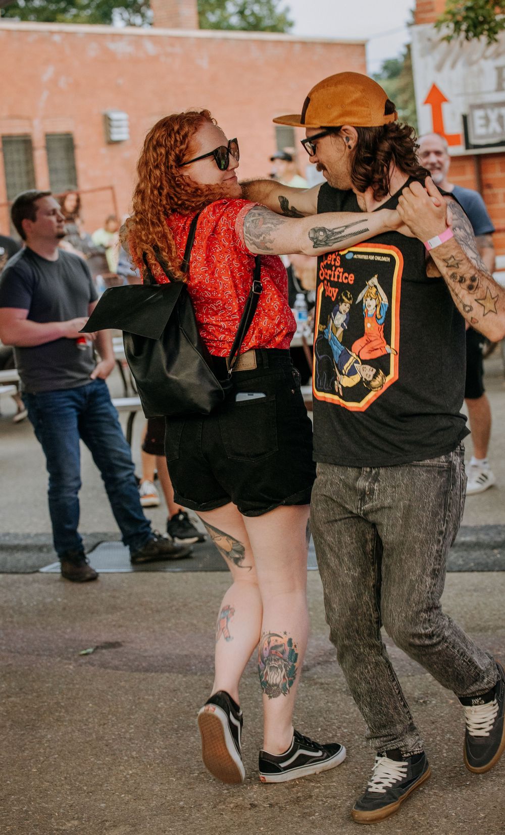 Couple dancing together at outdoor street festival with brick buildings in background.