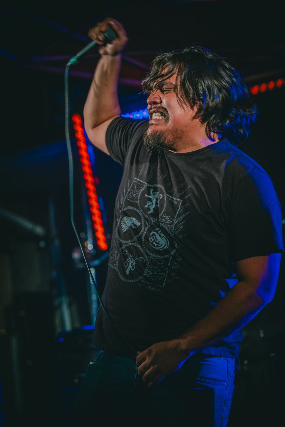 Energetic performer singing passionately into microphone during dark concert.