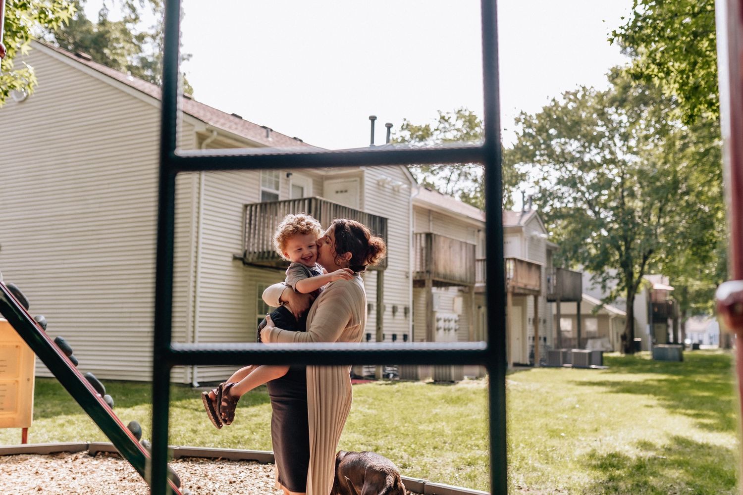 mom kissing son on the cheek while holding him at the playground