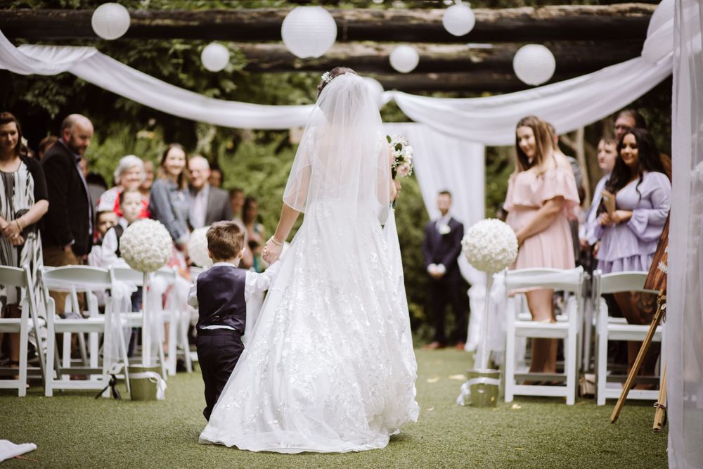 An outdoor wedding venue decorated with white fabric draping and elegant seating arrangements.