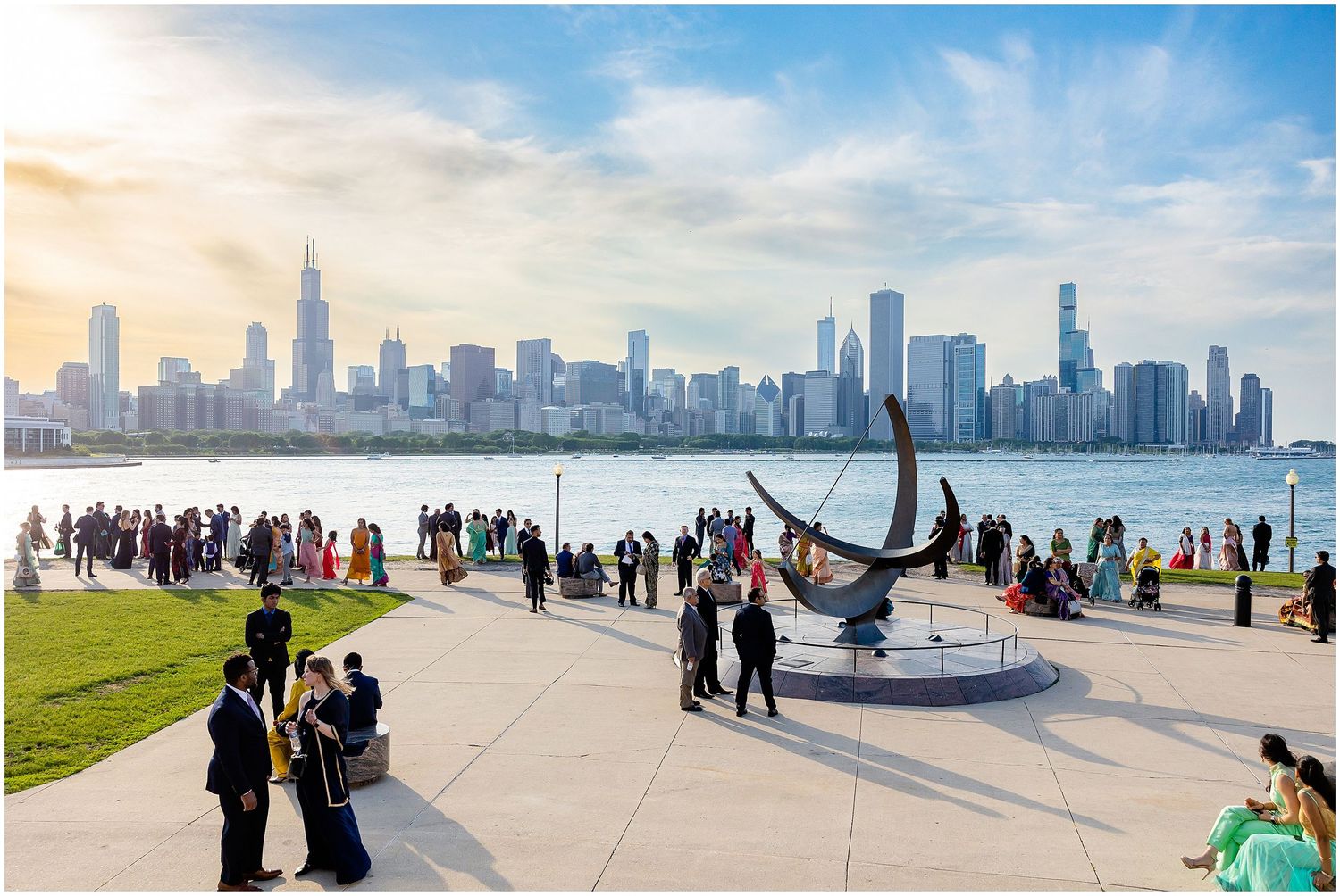 Chicago skyline viewed from lakefront with crowds gathering around anchor sculpture.