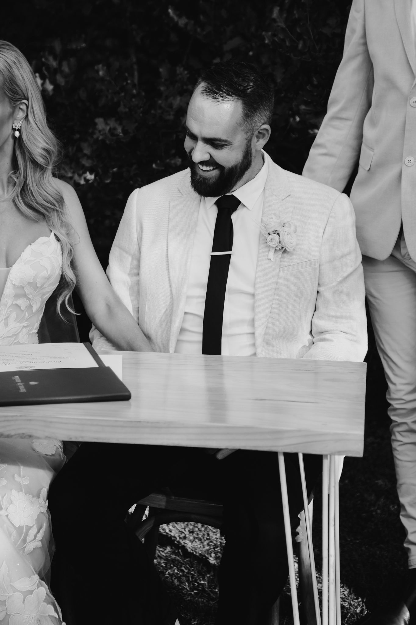Black and white photo of a joyful signing moment during a wedding ceremony.