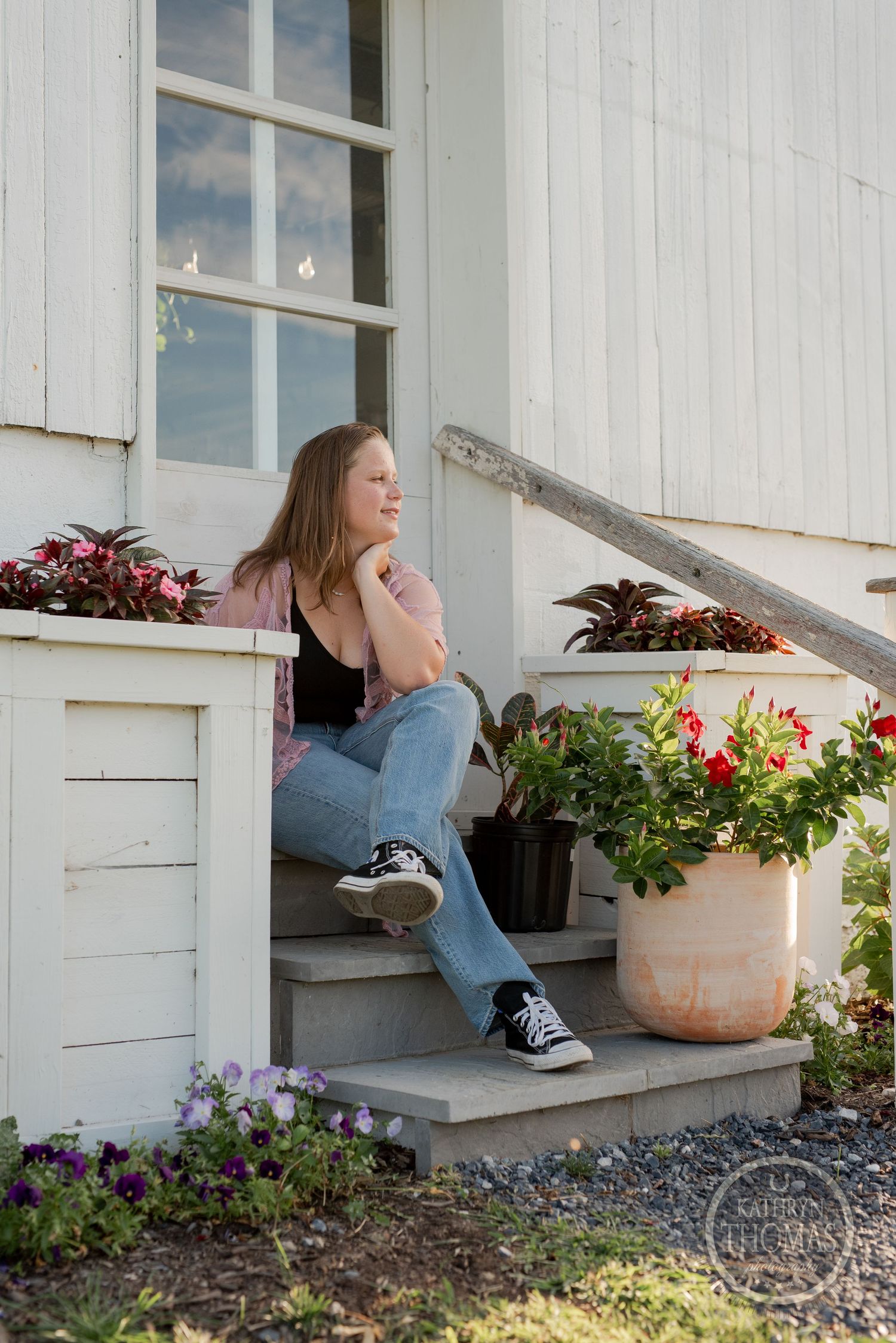 A relaxed portrait on farmhouse steps with decorative potted plants and white siding.