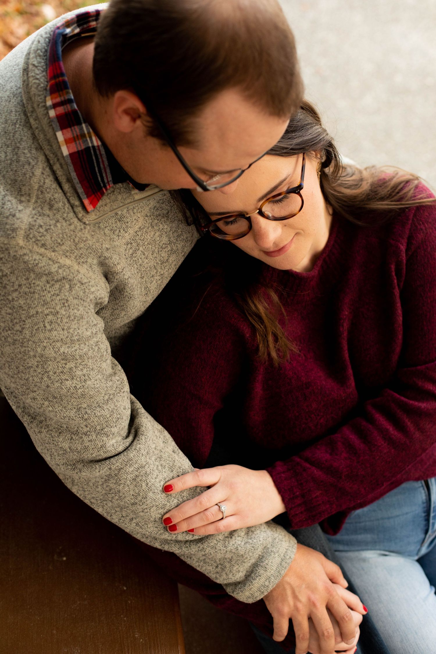 Cozy couple in sweaters sharing affectionate moment while wearing glasses.