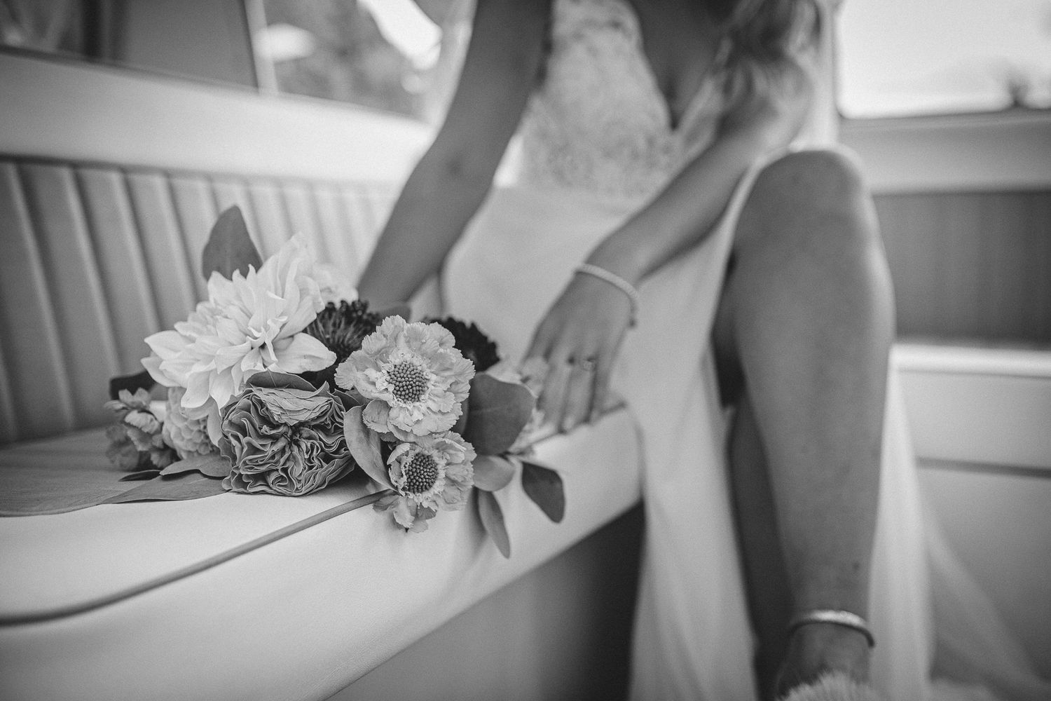 Close-up details of a wedding dress and floral bouquet in black and white.