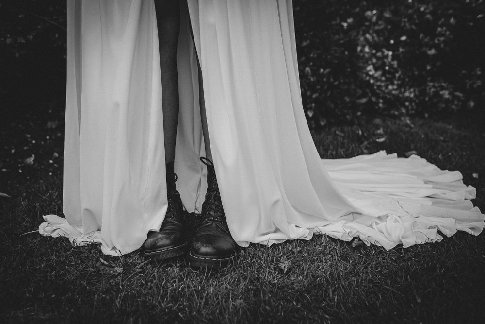 Black and white photo of wedding dress trains trailing on outdoor ground.
