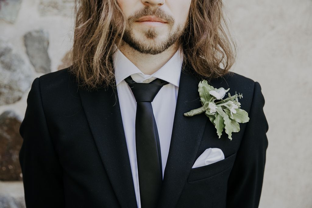 Detaljbild av knappnålsblomma/corsage. Bröllopsfotografering i Österhaninge kyrka utanför Stockholm.