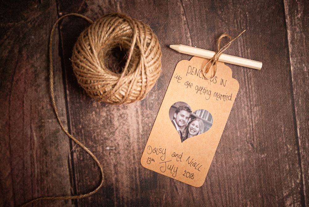 Vintage save-the-date tag with twine and photo on rustic wooden background.