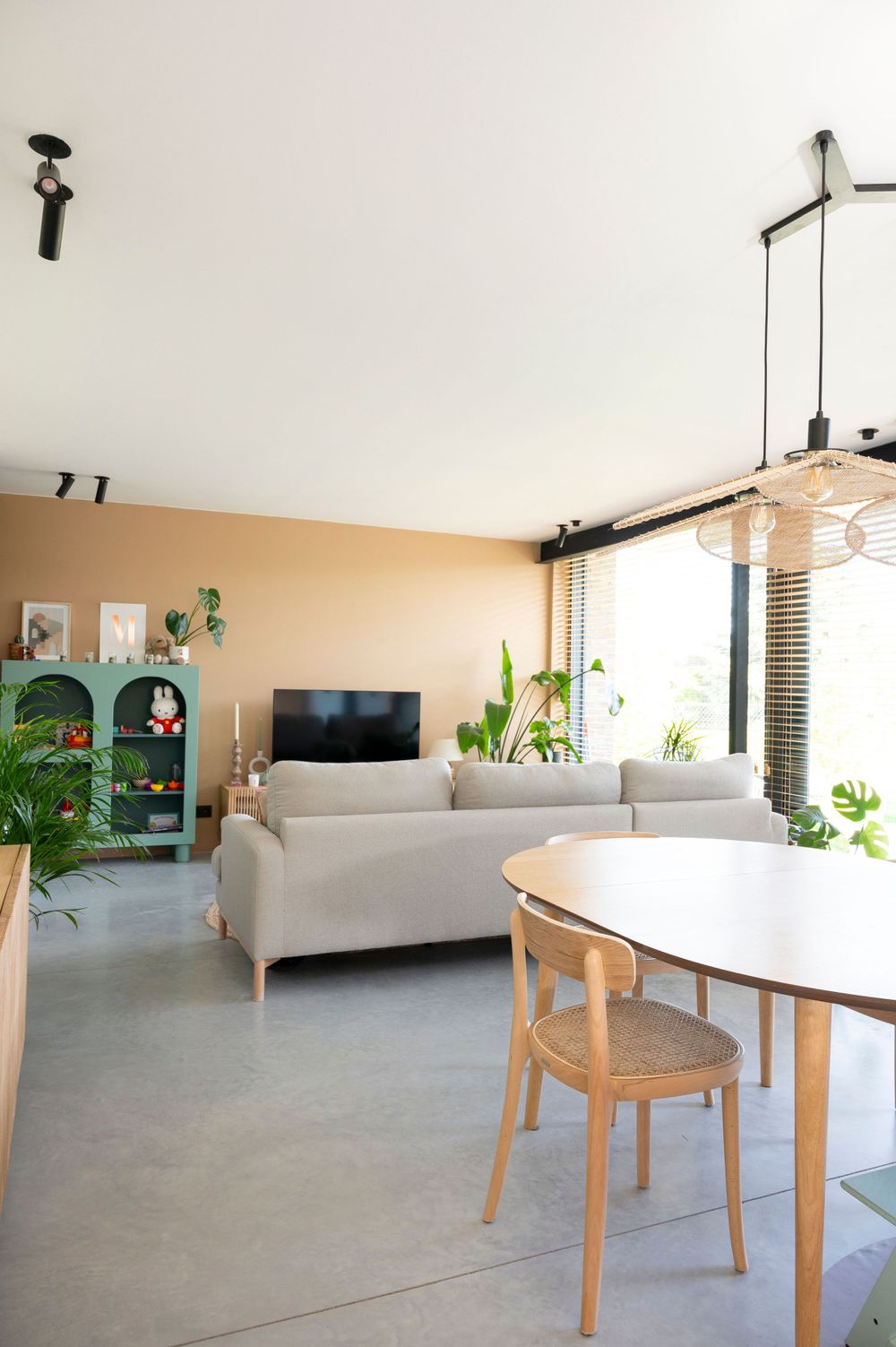 Contemporary open concept living area with white sofa, round dining table and wooden chairs.