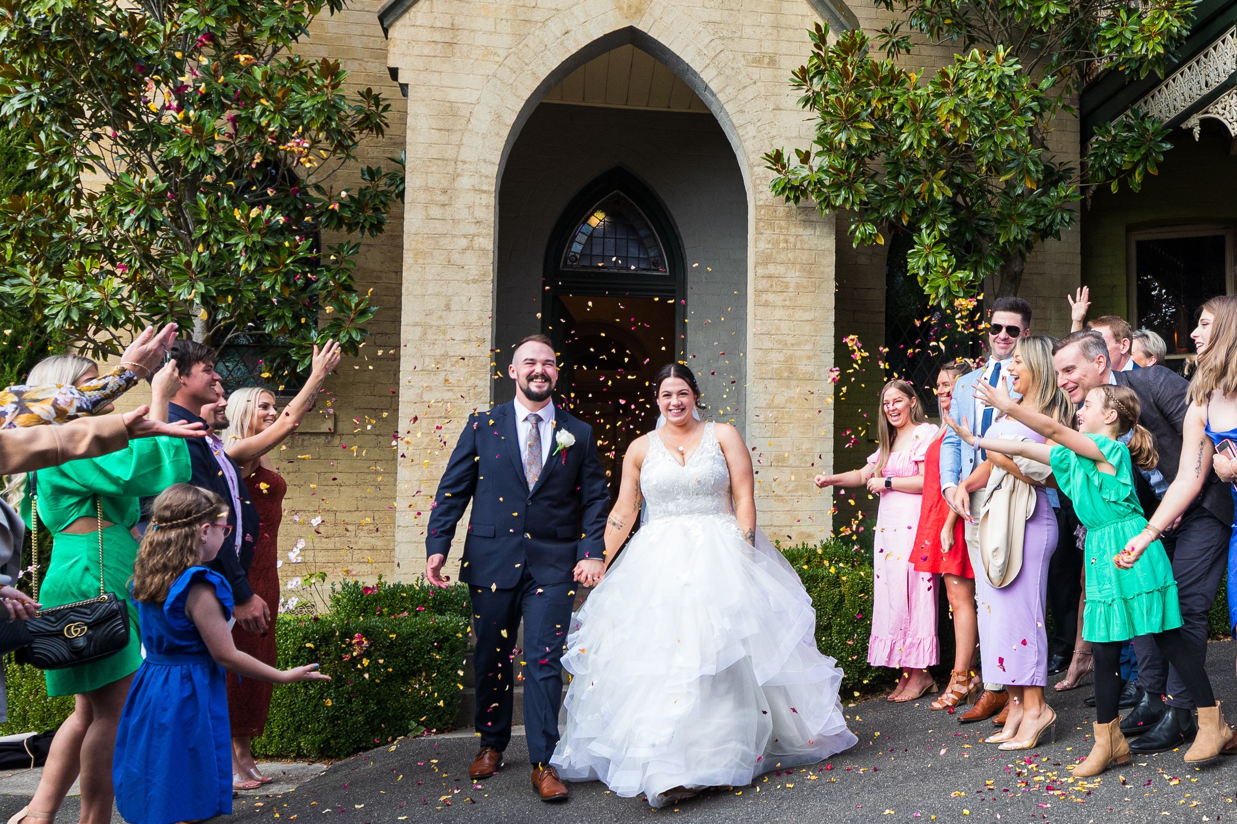 bride and groom exiting chapel covered in rose petals