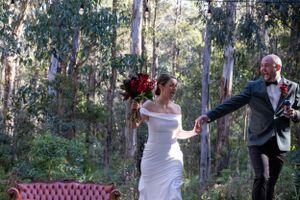 Bride and groom running laughing through forest.