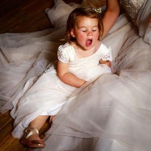young child, flower girl sitting in wedding dress yawning