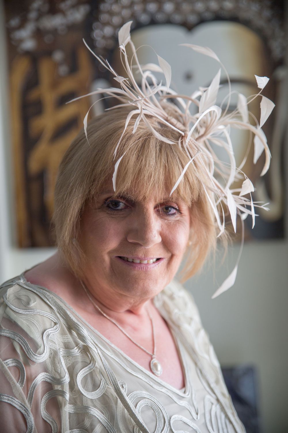 Woman wearing white lace dress with feather hair accessories getting ready for special occasion.