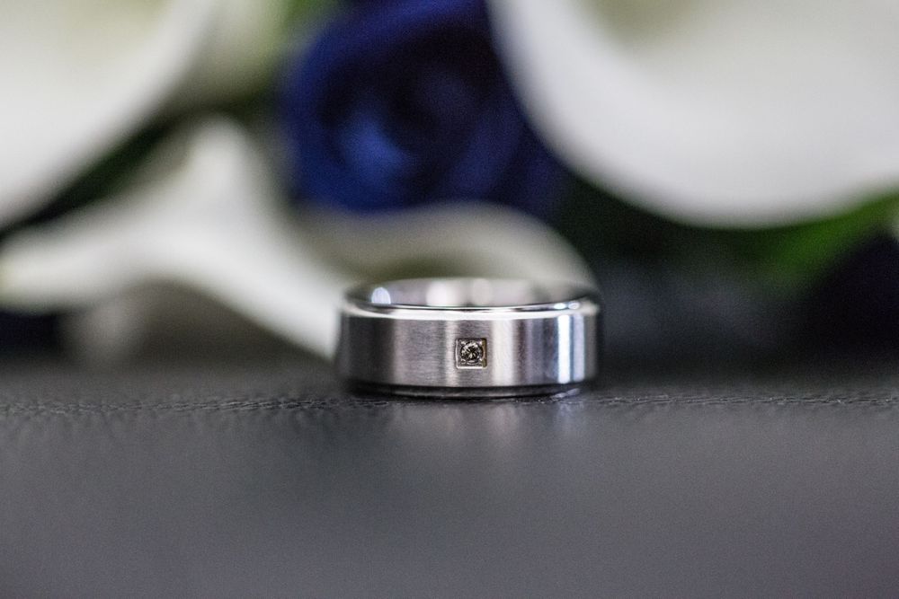 Close-up of silver wedding rings on dark surface with blurred background.