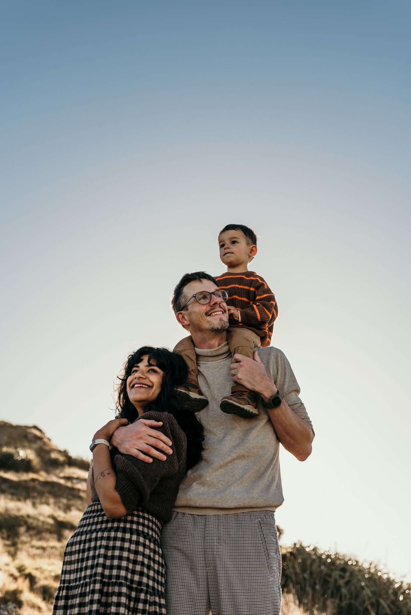A loving family embrace outdoors against a clear sky and rocky landscape.