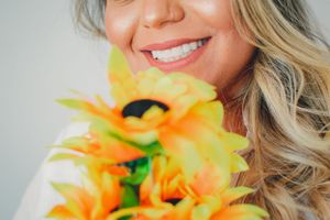Close-up fashion shots with vibrant yellow sunflowers contrasting against white clothing and blonde hair.