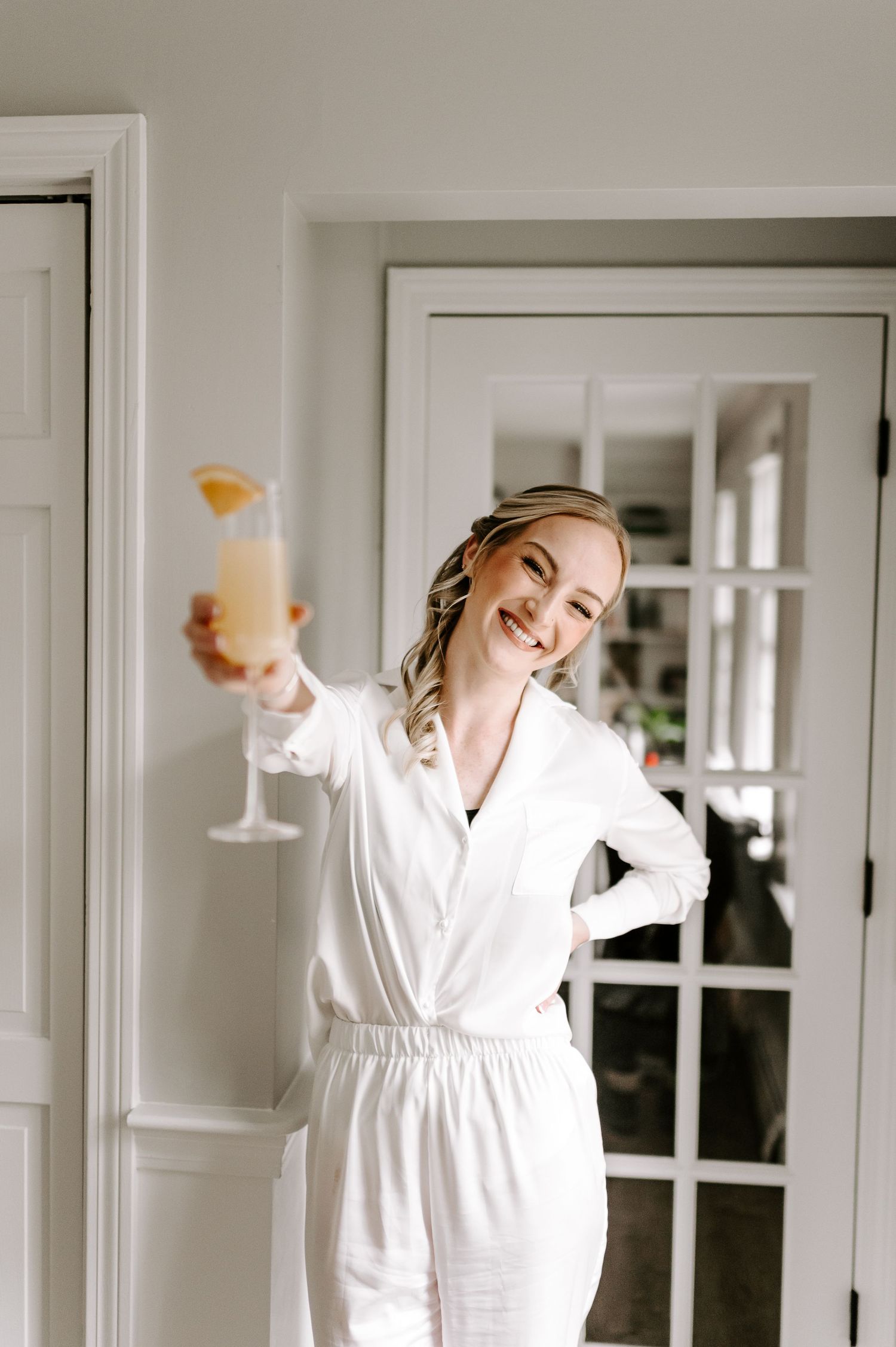 Person in white bathrobe dancing joyfully in a bright interior space.