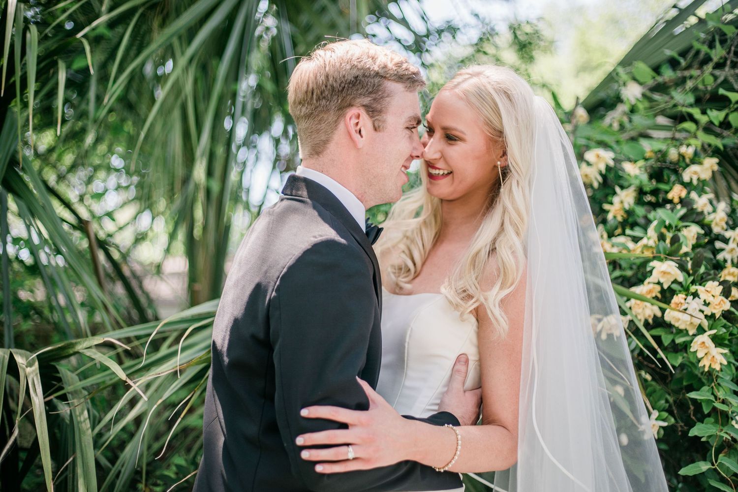 Newlyweds share an intimate moment among tropical foliage during their outdoor wedding photoshoot.