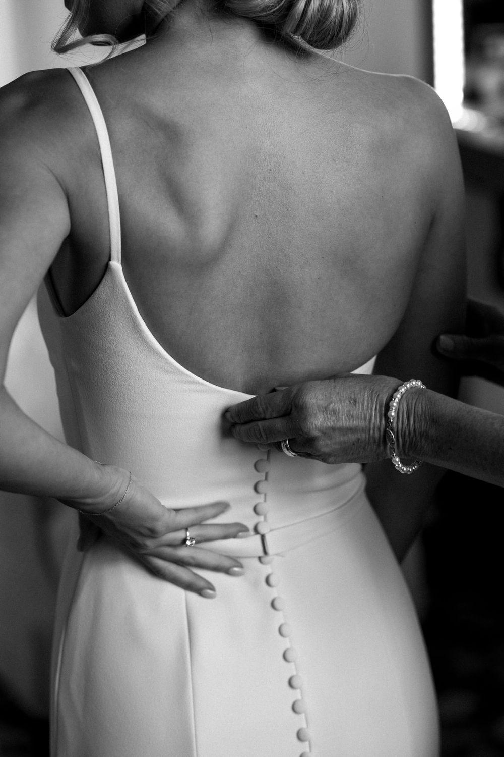 Close-up of buttoned details on the back of an elegant white wedding gown.