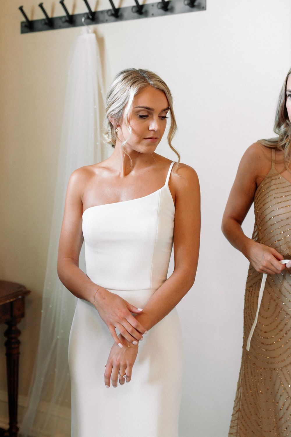 Elegant bride in a minimalist one-shoulder white gown with upswept hair.