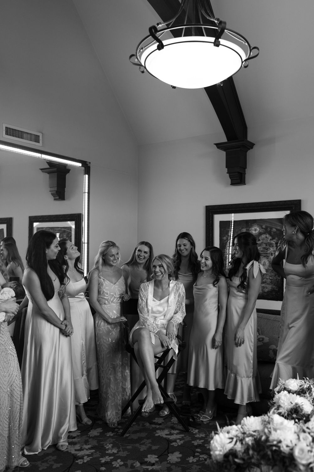 Joyful gathering of wedding party members in formal attire sharing candid moment indoors.