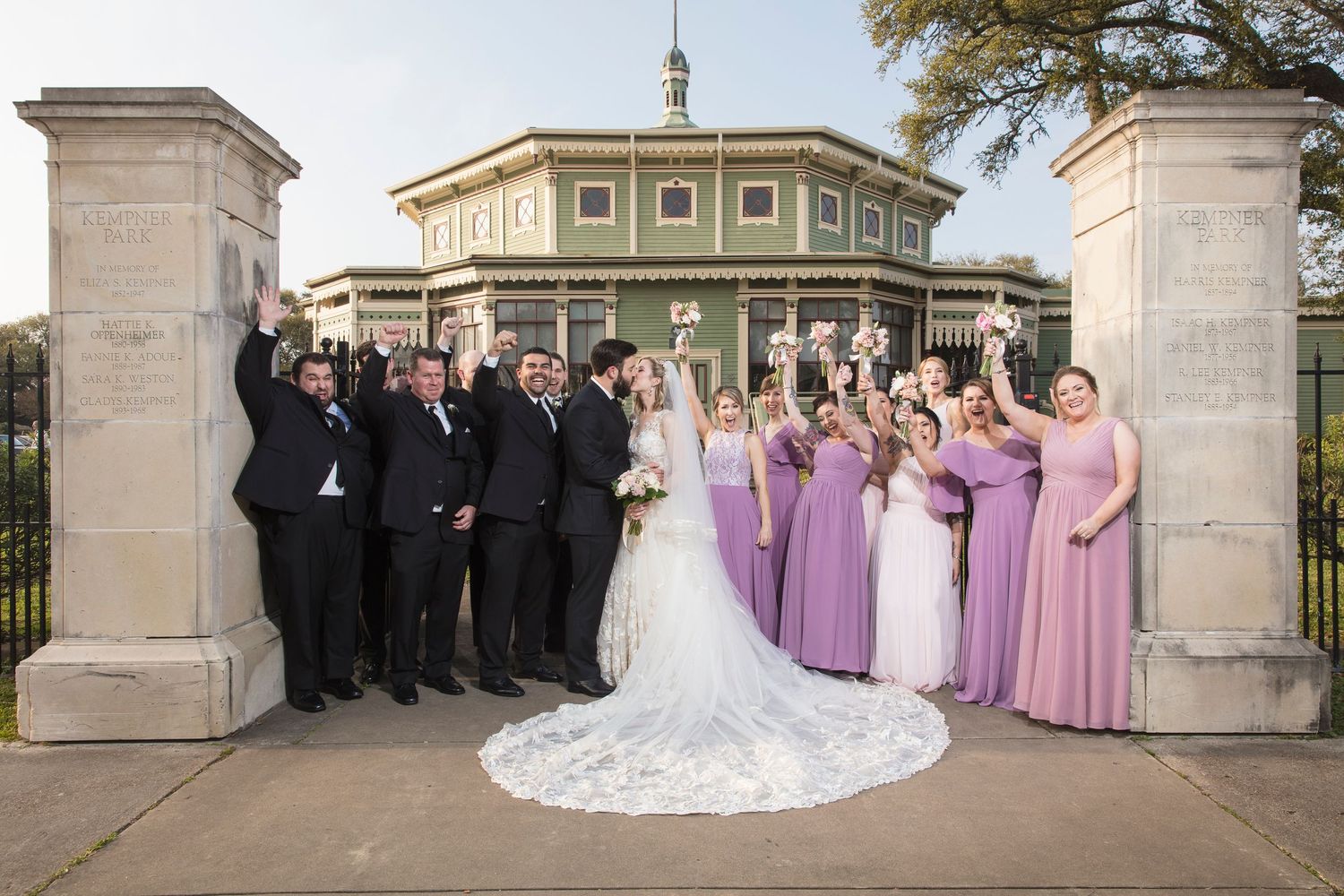 Wedding party arranged in formal group photos outside grand stone colonnade.