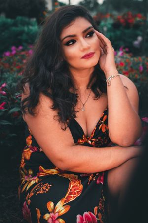 Glamour portrait in a garden featuring someone in a floral dress surrounded by colorful blooms.