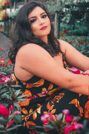 Outdoor portrait amid pink flowers with someone wearing a black and orange floral dress.