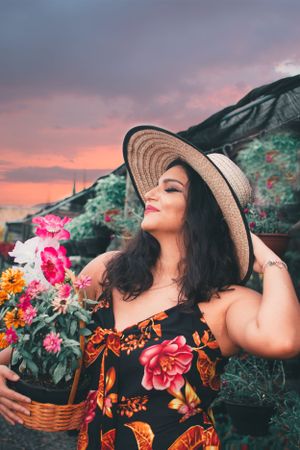 Dreamy sunset scene with someone in a straw hat holding a basket of vibrant flowers.